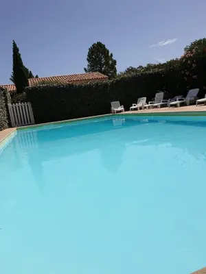 a large swimming pool with chairs in a yard at villa dans petite résidence avec piscine à 10 minutes des plages proche PORTO VECCHIO in Porto-Vecchio