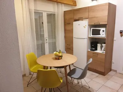 a kitchen with a table and chairs and a refrigerator at villa dans petite résidence avec piscine à 10 minutes des plages proche PORTO VECCHIO in Porto-Vecchio