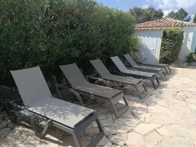 a row of lawn chairs sitting next to a hedge at villa dans petite résidence avec piscine à 10 minutes des plages proche PORTO VECCHIO in Porto-Vecchio