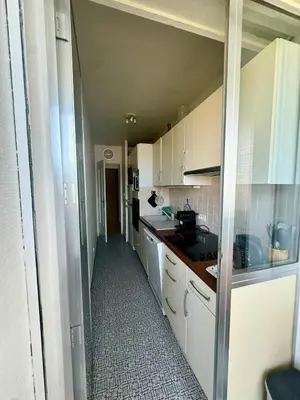 a small kitchen with white cabinets and a hallway at Studio cosy au cœur de Propriano in Propriano