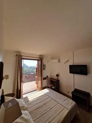 a hotel room with a bed and a balcony at T2 vue mer & montagne Golfe de Porto-Ota in Porto Ota