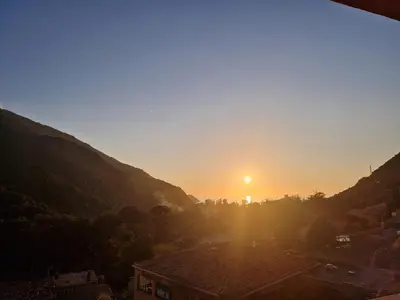 a view of the sun setting over a city at T2 vue mer & montagne Golfe de Porto-Ota in Porto Ota