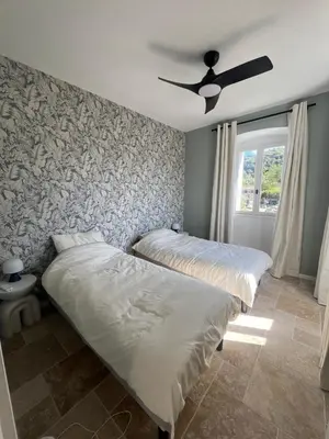 two beds in a bedroom with a ceiling fan at A Casa Laetizia in Eccica-Suarella