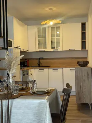 a kitchen with white cabinets and a table with glasses at Petite maison de village in Bastelica