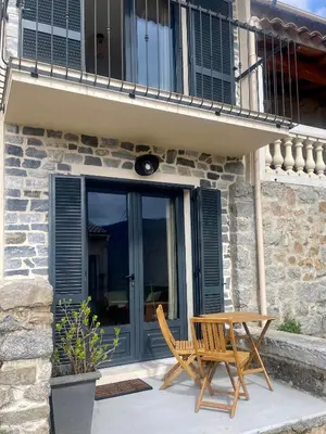 a patio with a wooden table and a chair at Petite maison de village in Bastelica