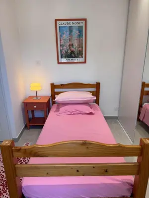 a bedroom with a wooden bed with a pink sheets at Appartement au cœur du village in Murato
