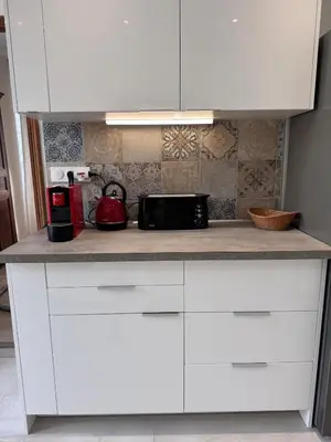 a kitchen counter with white cabinets and a microwave at Appartement au cœur du village in Murato