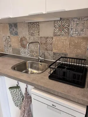 a kitchen with a stainless steel sink and tiles at Appartement au cœur du village in Murato