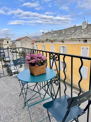 a table with a basket of flowers on a balcony at Appartement au cœur du village in Murato