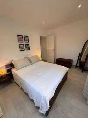 a bedroom with a large bed with white sheets at Appartement au cœur du village in Murato
