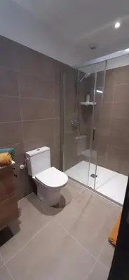 a bathroom with a toilet and a glass shower at Chez bigoudy in Penta-di-Casinca
