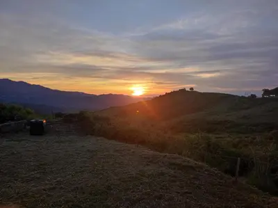 a sunset on a hill with the sun setting at Grand F2 vue montagne in Olmeta-di-Tuda