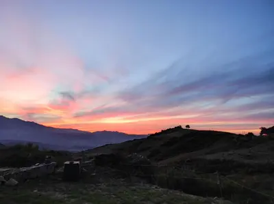 a sunset on top of a hill with a fence at Grand F2 vue montagne in Olmeta-di-Tuda