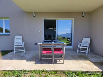 a patio with two chairs and a table and a window at Grand F2 vue montagne in Olmeta-di-Tuda