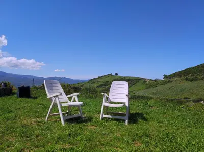 two chairs sitting in the grass on a hill at Grand F2 vue montagne in Olmeta-di-Tuda