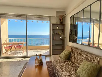 a living room with a couch and a view of the ocean at Appartement pieds dans l eau in Ajaccio