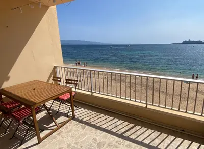 a table and chairs on a balcony overlooking the beach at Appartement pieds dans l eau in Ajaccio
