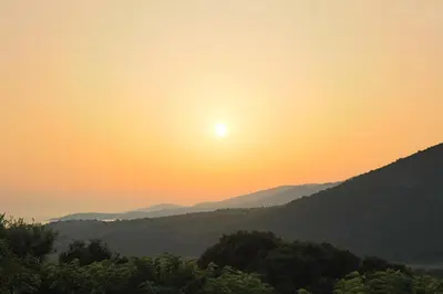 a view of the sun setting over a mountain range at Camping Les Couchants in Casaglione