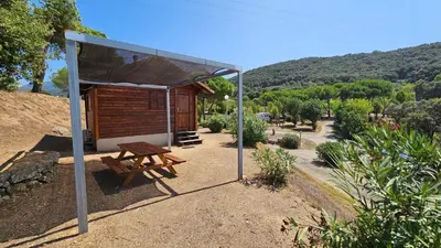 a building with a picnic table and a bench at Camping Les Couchants in Casaglione