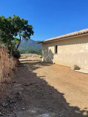 a dirt road next to a building with a tree at Villa vue montagne - 8 pers in Sotta