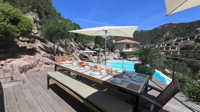 a table with food and an umbrella next to a pool at Secluded Villa With Sea View In Palombaggia in Porto-Vecchio