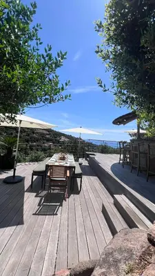 a wooden deck with a table and chairs on the beach at Secluded Villa With Sea View In Palombaggia in Porto-Vecchio