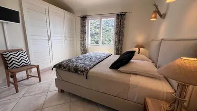 a bedroom with a bed and a window and a chair at Secluded Villa With Sea View In Palombaggia in Porto-Vecchio