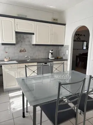 a kitchen with white cabinets and a glass table at Pietralba t3 in Ajaccio
