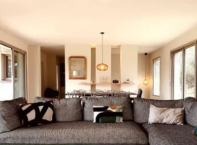 a living room with a couch and a kitchen at Chambre Cosy dans villa de standing avec piscine in Porto-Vecchio