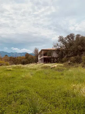 a house on a hill in a field of grass at Chambre Cosy dans villa de standing avec piscine in Porto-Vecchio