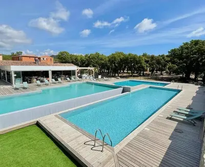 a large swimming pool with a wooden walkway around it at Cala Serena Saint Cyprien in Lecci