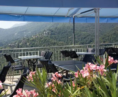 a balcony with tables and chairs and a view of a mountain at Le Refuge Orezza in Piedicroce
