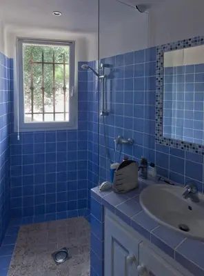 a blue tiled bathroom with a sink and a window at Boccamanza in Bonifacio