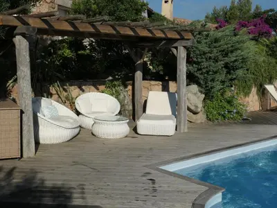 a group of chairs sitting under a pergola next to a pool at Boccamanza in Bonifacio