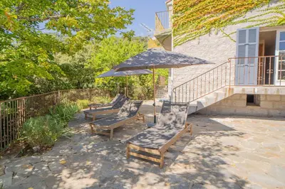 a group of chairs and an umbrella on a patio at Sud-corse bavella location montagne et mer in Sorbollano