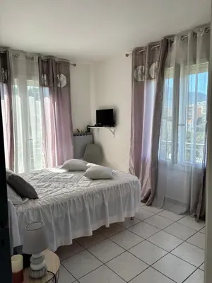 a bedroom with a bed with pink curtains and windows at CHARMANT T3 Pietralba in Ajaccio