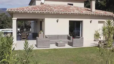 a white house with wicker chairs and a patio at Villa pour 8 avec piscine in Compoli