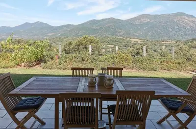 a wooden table and chairs with a view of mountains at Villa pour 8 avec piscine in Compoli
