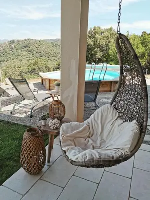a swinging chair on a patio with a pool at Villa pour 8 avec piscine in Compoli