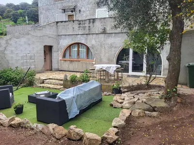a garden with a table and a couch on the grass at Appartement calme, authentique et spacieux au pied du GR20 in Calenzana