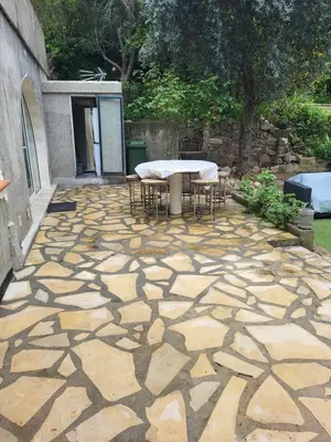 a stone patio with a table and chairs on it at Appartement calme, authentique et spacieux au pied du GR20 in Calenzana