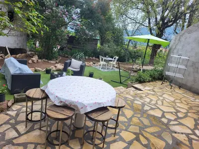 a patio with a table and chairs and an umbrella at Appartement calme, authentique et spacieux au pied du GR20 in Calenzana