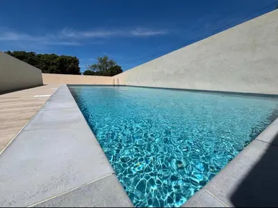 a swimming pool with blue water in front of a building at Résidence privée avec piscine à Bonifacio in Bonifacio
