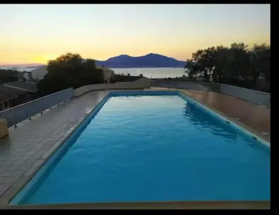 a large blue swimming pool with a view of the ocean at Petit cocon in Porticcio