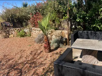a table and a palm tree in a garden at Chambre cosy à 5 min de la plage in Viagenti