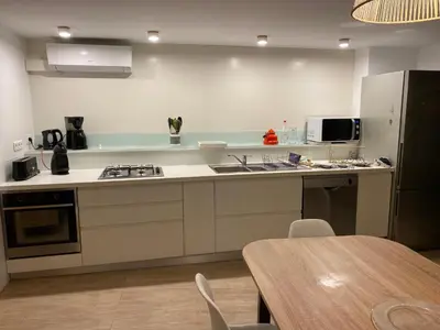 a kitchen with white counters and a table with chairs at Corse du Sud Villa les pieds dans l'eau ! in Zonza
