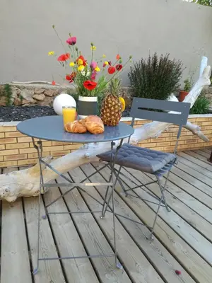 a table and a chair with flowers on a patio at Corse du Sud Villa les pieds dans l'eau ! in Zonza
