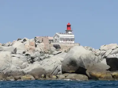 a lighthouse on the rocks with a red lighthouse at Corse du Sud Villa les pieds dans l'eau ! in Zonza