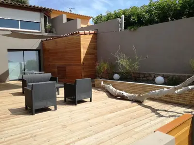 a patio with two chairs and a table on a wooden deck at Corse du Sud Villa les pieds dans l'eau ! in Zonza