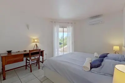 a white bedroom with a desk and a bed at Villa Lorinadu Vue mer Plage à 800m à pied in Zonza
